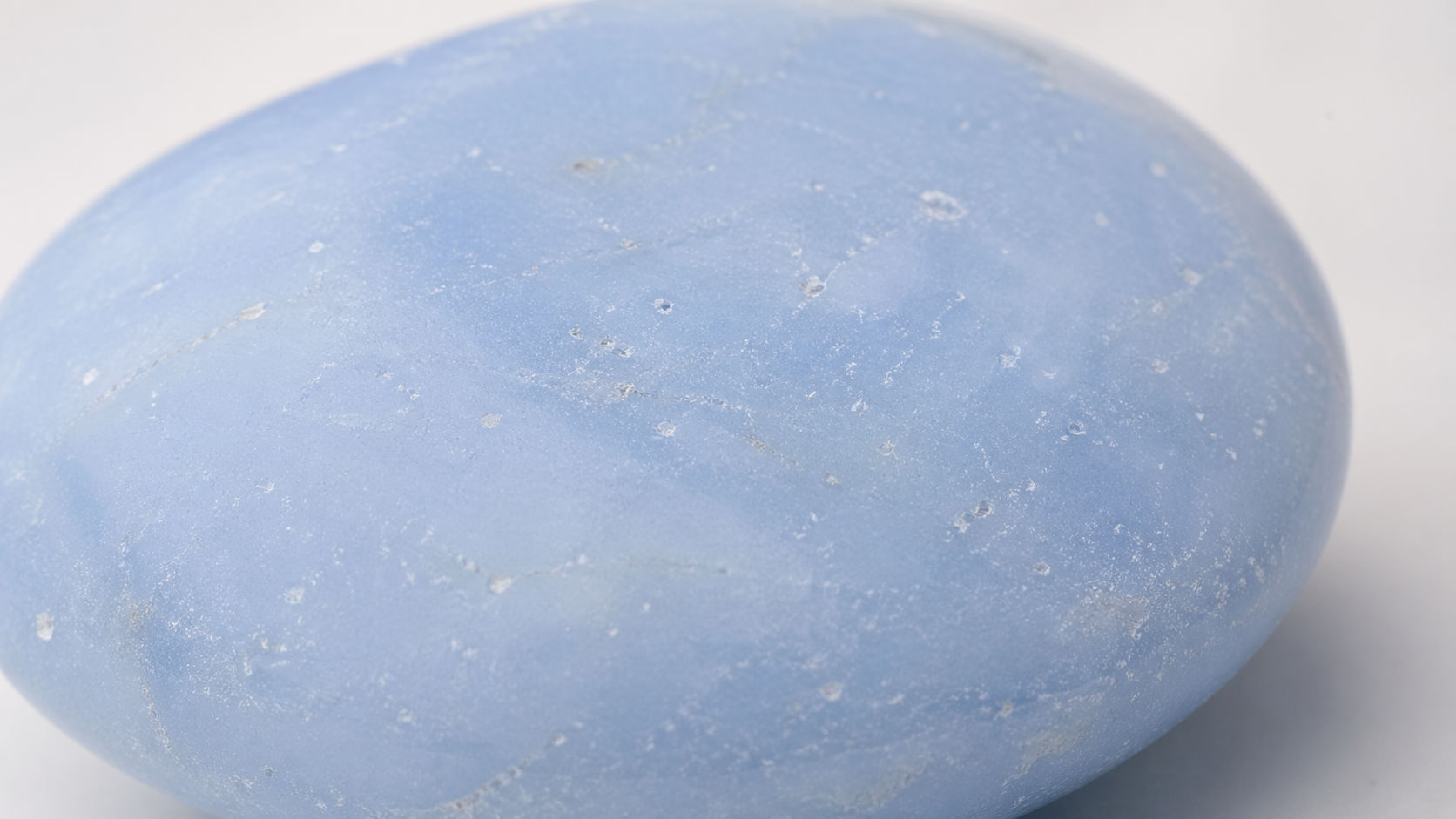 Piedra Angelita de color azul cielo mate y suave, rodeada de una luz blanca etérea para Umbral Astral.